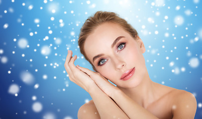 Image showing beautiful young woman face and hands over snow