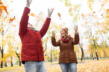 Image showing happy young couple throwing autumn leaves in park