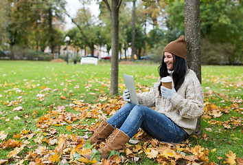 Image showing woman with tablet pc and coffee in autumn park