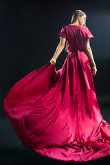 Image showing Back view of young blonde woman in bright pink dress