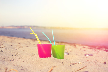 Image showing Colorful drink cups in the sand