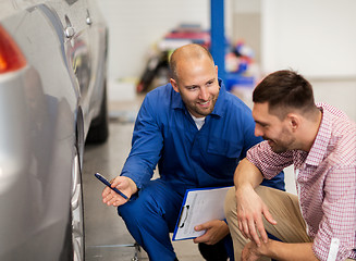 Image showing auto mechanic with clipboard and man at car shop