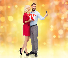 Image showing happy couple with smartphone and gift boxes