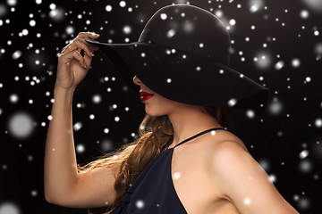 Image showing beautiful woman in black hat over snow