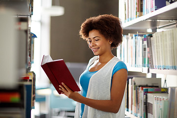 Image showing happy african student girl reading book at library