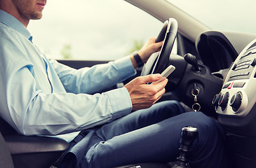 Image showing close up of man with smartphone driving car