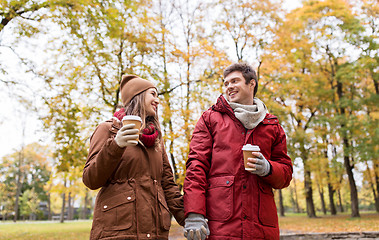 Image showing happy couple with coffee walking in autumn park