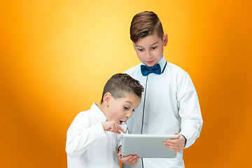 Image showing The two boys using laptop on orange background