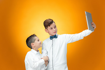 Image showing The two boys using laptop on orange background