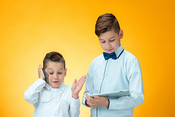 Image showing The two boys using laptop on orange background