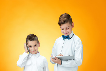 Image showing The two boys using laptop on orange background