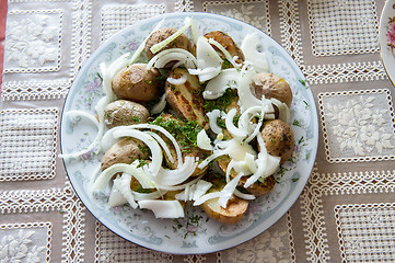 Image showing Russian Traditional baked potatoes with the peel, onion and fennel, drizzled oil on a plate gray ornament