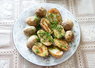 Image showing Russian Traditional baked potatoes with the peel and fennel, drizzled  oil on a plate   gray ornament