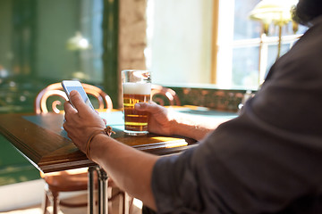 Image showing close up of man with smartphone and beer at pub