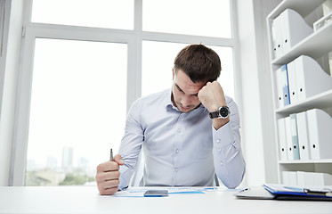 Image showing stressed businessman with papers in office