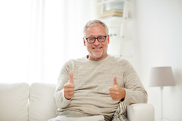 Image showing smiling senior man showing thumbs up at home