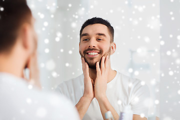 Image showing happy young man looking to mirror at home bathroom