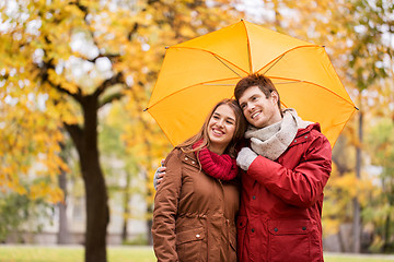 Image showing smiling couple with umbrella in autumn park