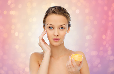 Image showing young woman applying cream to her face