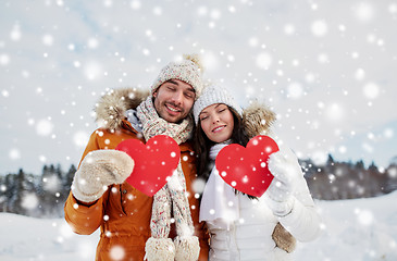 Image showing happy couple with red hearts over winter landscape