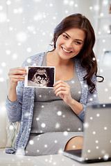 Image showing happy pregnant woman with ultrasound image at home