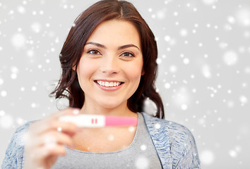 Image showing happy smiling woman holding home pregnancy test