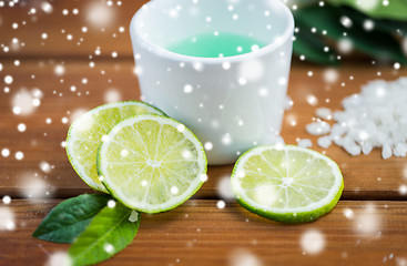 Image showing close up of body lotion in cup and limes on wood