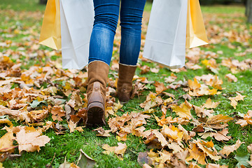 Image showing woman with shopping bags walking along autumn park