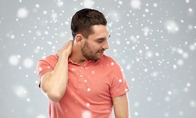 Image showing unhappy man suffering from neck pain over snow