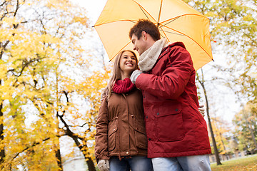 Image showing smiling couple with umbrella in autumn park