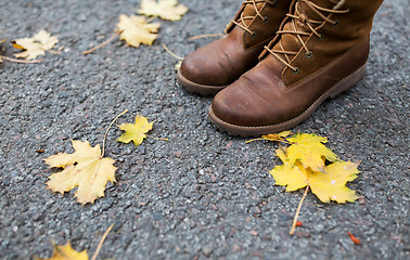 Image showing female feet in boots and autumn leaves