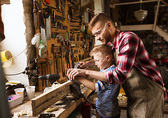 Image showing father and son with plane shaving wood at workshop