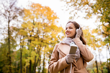 Image showing woman with smartphone and earphones in autumn park