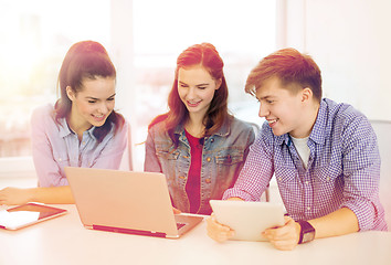 Image showing three smiling students with laptop and tablet pc