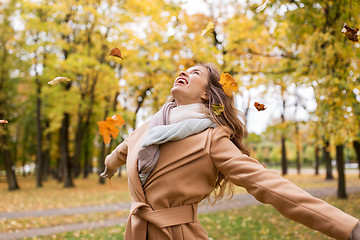 Image showing happy woman having fun with leaves in autumn park