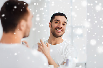 Image showing man with perfume looking to mirror at bathroom