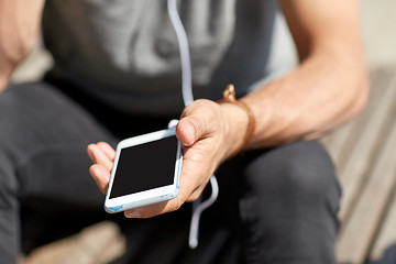 Image showing close up of man with smartphone and earphones wire