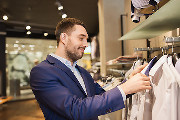 Image showing happy young man choosing clothes in clothing store