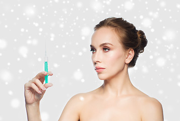 Image showing woman holding syringe with injection over snow