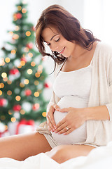 Image showing happy pregnant woman making heart at christmas