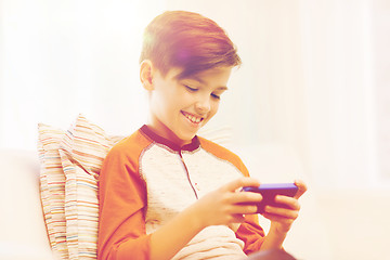 Image showing boy with smartphone texting or playing at home