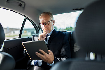 Image showing senior businessman with tablet pc driving in car