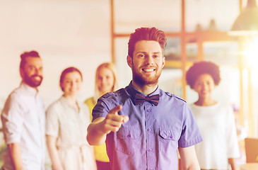 Image showing happy man pointing finger at you over office team