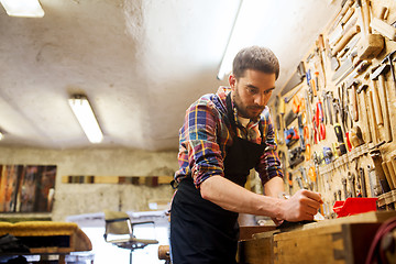 Image showing carpenter working with plane and wood at workshop