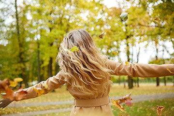 Image showing happy woman having fun with leaves in autumn park