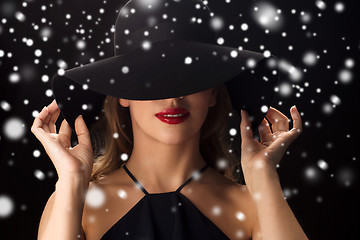 Image showing beautiful woman in black hat over snow