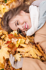 Image showing beautiful happy woman lying on autumn leaves