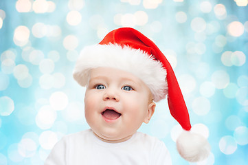 Image showing baby boy in christmas santa hat over blue lights