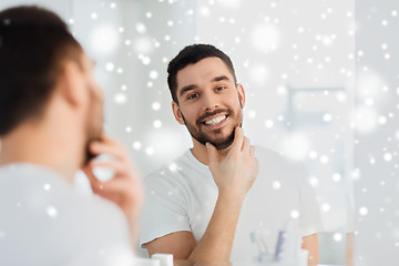 Image showing happy young man looking to mirror at home bathroom