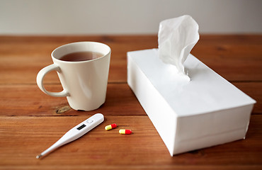 Image showing cup of tea, paper wipes and thermometer with pills